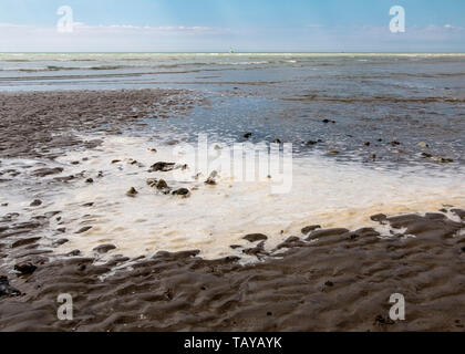 Sea Foam bilden am Strand in Worthing, West Sussex, Großbritannien Stockfoto