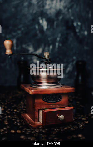Alten hölzernen Kaffeemühle und Kaffeebohnen auf konkreten Hintergrund. Stockfoto