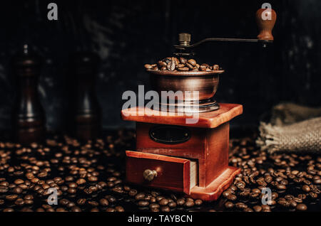 Alten hölzernen Kaffeemühle und Kaffeebohnen auf konkreten Hintergrund. Stockfoto