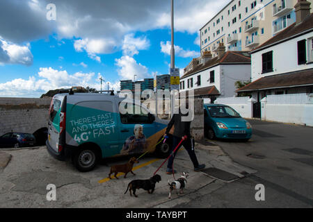 Hund zu Fuß in Gibraltar an der Küste Mann zu Fuß mit seinen Hunden an der Küste dunkle schwarze Wolken Regen Straße Van geparktes Auto Haus Blick auf Häuser Stockfoto