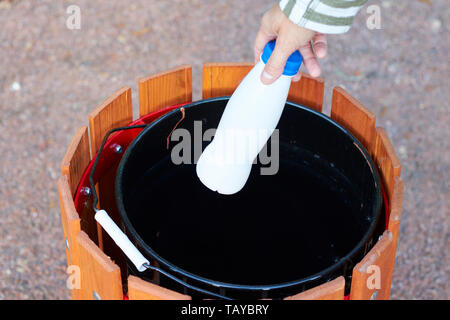 Woman's Hand wirft leere Wasserflasche in Stadt Straße Mülleimer auf sonnigen Tag, close-up Stockfoto