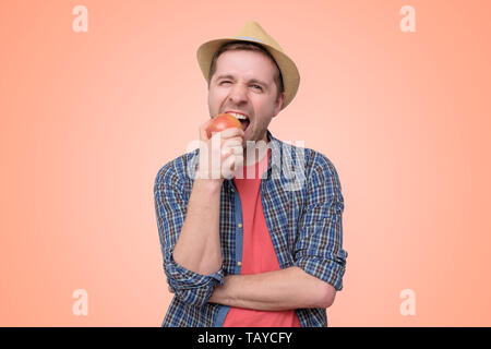 Mann im Sommer Hut eatin Gresh roten Apfel. Stockfoto