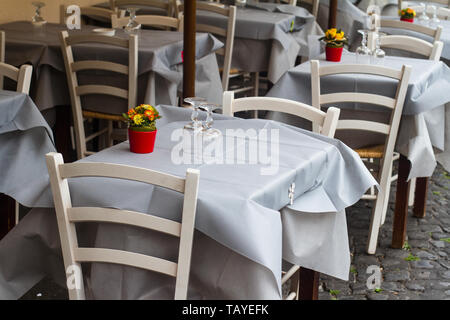 Perspektivische Ansicht Nahaufnahme von traditionellen italienischen Street Restaurant Terrasse mit weißen Tischen und Stühlen auf alten Gehweg Stockfoto