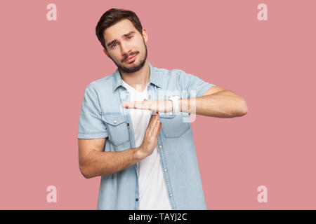 Ich brauche mehr Zeit. Portrait von Sorge gut aussehender bärtiger junger Mann in blau casual style Hemd mit timeout Geste und für mehr Zeit bettelte. ind Stockfoto