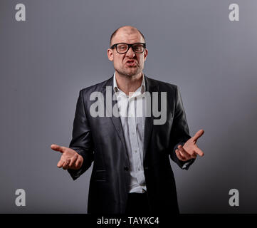 Unzufrieden laut schreien business Mann mit grimasse wütend das Gesicht im Büro Anzug und Brille auf grauem Hintergrund. Closeup Portrait Stockfoto