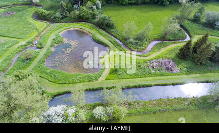 Luftaufnahme der Gehwege, Gehwege rund um Teich, Bäche durch Frühlingswiesen in ländlichen englischen Landschaft. Stockfoto