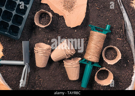 Seeding tomate Ausrüstung und Boden - biologisch abbaubar Karton Töpfe, Gartengeräte und Tomatensamen bereit für die Aussaat, Ansicht von oben flach Stockfoto