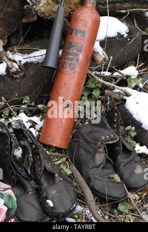 Die Abbildung zeigt eine altmodische verworfen Feuerlöscher neben zwei Paar abgenutzt abgewetzte Leder Stiefel draußen im Schnee Stockfoto