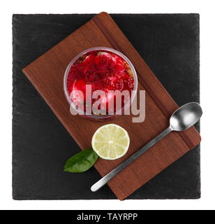 Raspberry cheesecake Dessert in einem Glas auf einen schwarzen Stein Platte auf weißem Hintergrund Stockfoto