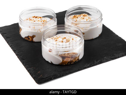 Honig cheesecake Dessert in einem Glas auf einen schwarzen Stein Platte auf weißem Hintergrund Stockfoto