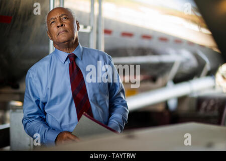 Schwere reifen Geschäftsmann runzelt die Stirn, als er schaut über Öltanker in der industriellen Hof. Stockfoto