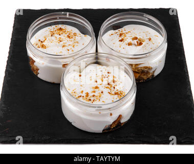Honig cheesecake Dessert in einem Glas auf einen schwarzen Stein Platte auf weißem Hintergrund Stockfoto