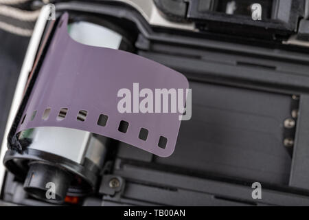 Von alten analogen Kamera und Schwarzen und Weißen neuen Film. Zubehör für die analoge Fotografie auf einen dunklen Tisch. Schwarzen Hintergrund. Stockfoto