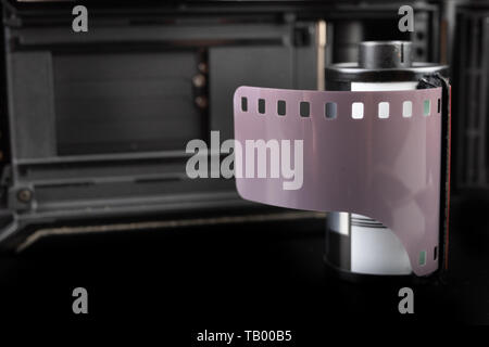 Von alten analogen Kamera und Schwarzen und Weißen neuen Film. Zubehör für die analoge Fotografie auf einen dunklen Tisch. Schwarzen Hintergrund. Stockfoto