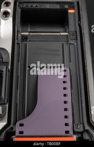 Von alten analogen Kamera und Schwarzen und Weißen neuen Film. Zubehör für die analoge Fotografie auf einen dunklen Tisch. Schwarzen Hintergrund. Stockfoto