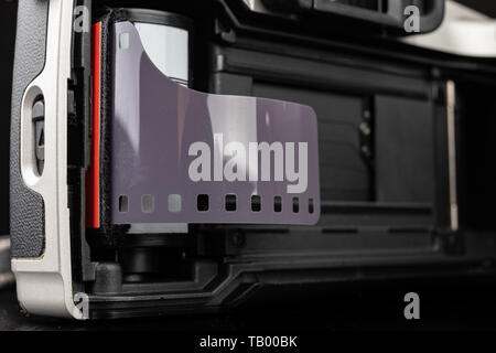 Von alten analogen Kamera und Schwarzen und Weißen neuen Film. Zubehör für die analoge Fotografie auf einen dunklen Tisch. Schwarzen Hintergrund. Stockfoto