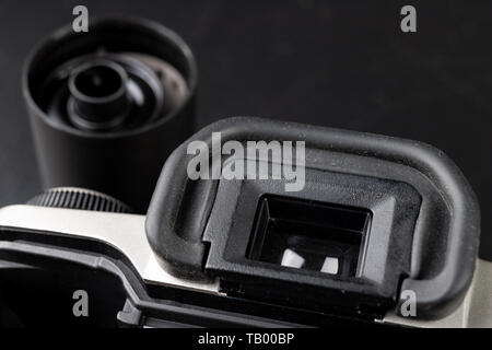 Von alten analogen Kamera und Schwarzen und Weißen neuen Film. Zubehör für die analoge Fotografie auf einen dunklen Tisch. Schwarzen Hintergrund. Stockfoto