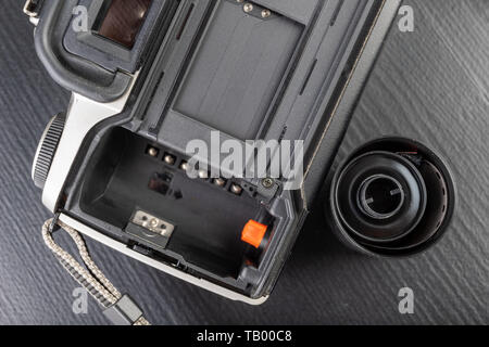 Von alten analogen Kamera und Schwarzen und Weißen neuen Film. Zubehör für die analoge Fotografie auf einen dunklen Tisch. Schwarzen Hintergrund. Stockfoto