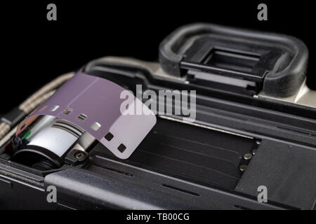 Von alten analogen Kamera und Schwarzen und Weißen neuen Film. Zubehör für die analoge Fotografie auf einen dunklen Tisch. Schwarzen Hintergrund. Stockfoto