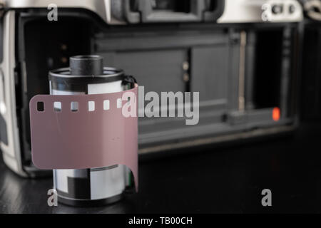 Von alten analogen Kamera und Schwarzen und Weißen neuen Film. Zubehör für die analoge Fotografie auf einen dunklen Tisch. Schwarzen Hintergrund. Stockfoto