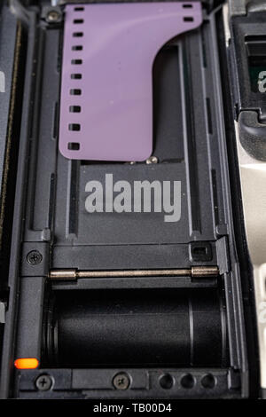 Von alten analogen Kamera und Schwarzen und Weißen neuen Film. Zubehör für die analoge Fotografie auf einen dunklen Tisch. Schwarzen Hintergrund. Stockfoto