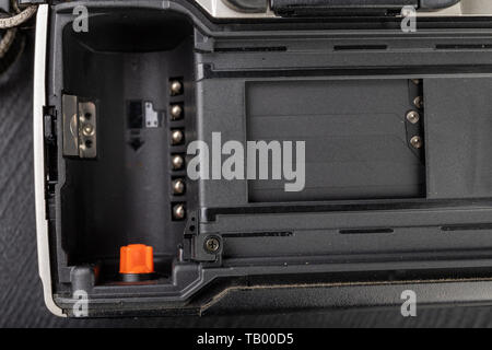 Von alten analogen Kamera und Schwarzen und Weißen neuen Film. Zubehör für die analoge Fotografie auf einen dunklen Tisch. Schwarzen Hintergrund. Stockfoto