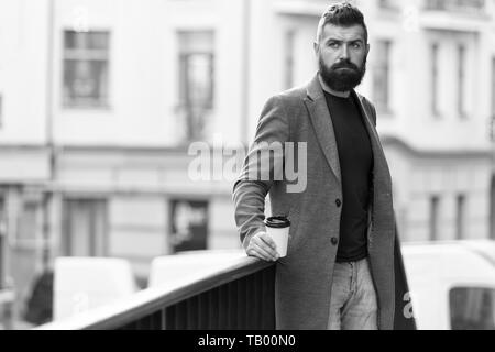 Man bärtige hipster Kaffee trinken Pappbecher. Noch ein Schluck Kaffee. Stadt Lebensstil. Geschäftsmann gepflegt aussehen genießen Sie Kaffee Pause aus Business Center im städtischen Hintergrund. Entspannen und erholen Sie sich. Stockfoto