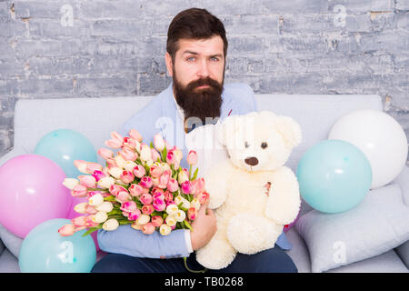 Mann gut gepflegt Verschleiß tuxedo Bow Tie halten Blumen Tulpen Bouquet und großen Teddybären Spielzeug. Laden Sie dating. Romantisches Geschenk. Romantischen Mann. Macho fertig, romantisches Date. Warten auf Darling. Stockfoto