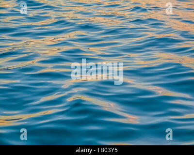 Das ruhige Wasser schimmert mit den goldenen Reflexen des Sonnenuntergangs Stockfoto