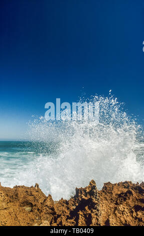 Große Welle über felsige Küstenlinie explodierende Stockfoto