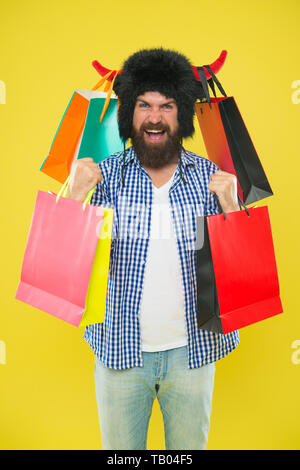 Wunderbare erwerben. Bärtiger Mann lächelnd mit persönlichen erwerben. Happy Hipster in Stier Hörner hat seinen Kauf in paperbags. Kaufen Mode kaufen. Stockfoto