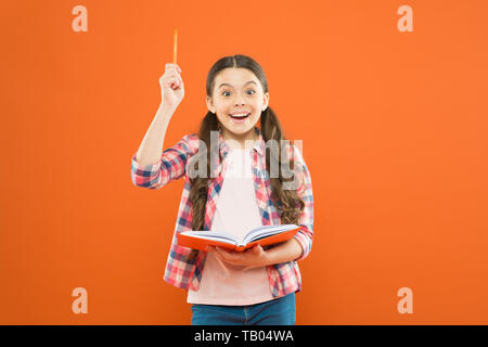 Das Buch hat mir einige Ideen. Kleines Mädchen schreiben Ihre Idee in ein Tagebuch. Kleines Kind Pen nach oben in geniale Idee. Adorable Schülerin erhielt Grundidee des Buches. Stockfoto