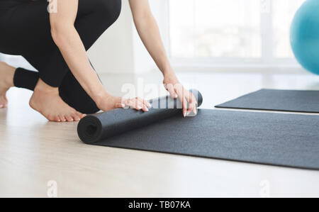 Zugeschnittenes Bild der weiblichen Händen rolling Yoga Matte Stockfoto