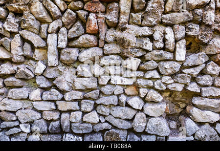 Verwitterter stein Wand als kreative Hintergrund Textur. Natursteine Mauerwerk mit ungleichmäßige Nähte. Rauer stein Wand Textur Stockfoto