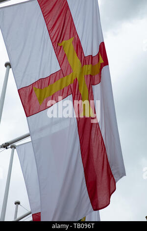 Flagge Guernsey Vogtei Guernsey fliegen in den Wind. Parliament Square, London, UK in der Feier von Crown Dependencies und Überseeische Gebiete Stockfoto