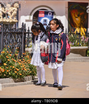 Bolivianische Kinder, die auf der Plaza de 10 Noviembre im kolonialen Potosí, Bolivien, spazieren gehen Stockfoto