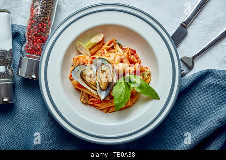 Nudeln mit Meeresfrüchten und Tomatensauce. Penne mit Garnelen, Tintenfisch, Muscheln, Vongli in Tomatensauce mit Basilikum Stockfoto