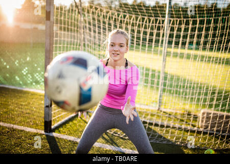 Jugendlich weiblichen goalie fängt einen Schuß während ein Fußball-Spiel Stockfoto