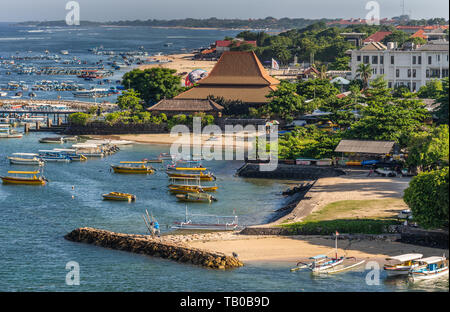 Hafen Benoa, Bali, Indonesien - Februar 26, 2019: Nahaufnahme von Strand, Pier, Boote, Resort und Unternehmen an der Spitze der Tanyung Benoa Halbinsel über dunklen Stockfoto