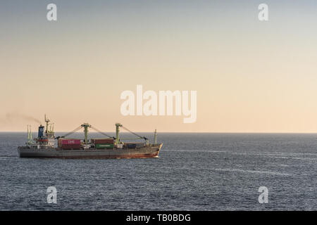 Die Bucht von Benoa, Bali, Indonesien - 26. Februar 2019: Grau Rot Meratus Sabang General Cargo Schiff segelt auf Benoa Bucht bei Sonnenuntergang. Dunkleren blauen Meer Wasser und Stockfoto