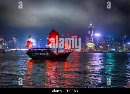 Hong Kong. China. Juni 13, 2016. Schiff mit roten Segeln auf dem Hintergrund einer Nacht Stadt mit hellen Lichtern in Hongkong. Stockfoto