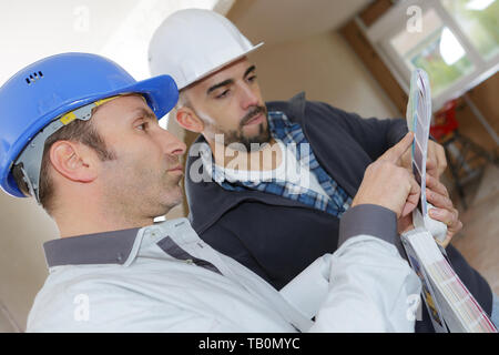 Mittleres Alter männlicher Techniker und Vorarbeiter diskutieren auf der Baustelle Stockfoto