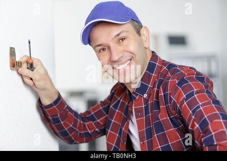 Man Verschrauben an der Wand Stockfoto