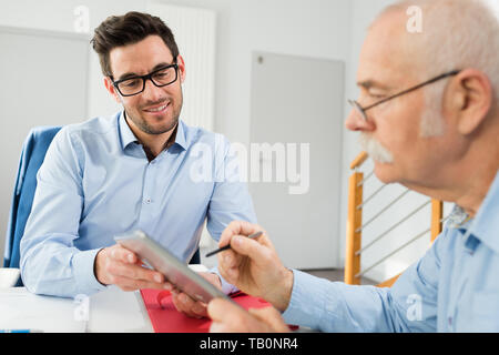 Zwei Männer in business meeting an Tablet suchen Stockfoto