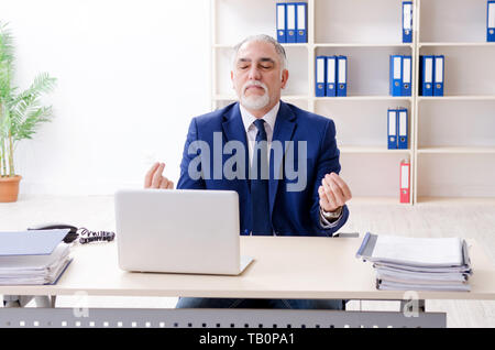 Alter Geschäftsmann Yoga Übungen im Büro Stockfoto
