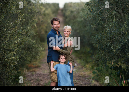 Junge Familie mit zwei kleinen Tochter im Freien in Olivenbaum Obstgarten stehen. Stockfoto