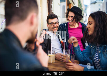 Eine Gruppe junger Freunde, die in einem Café im Freien sitzen und sich unterhalten. Stockfoto