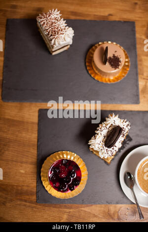 Blick von oben auf die süßen verzierten Kuchen mit frischen Früchten in einem Coffee Shop. Kuchen mit weißen Sahne. Kuchen mit leckeren Keks. Stockfoto