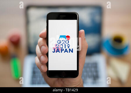 Ein Mann schaut auf seinem iPhone die zeigt die G 20 2019 Osaka Japan Gipfel Logo (nur redaktionelle Nutzung). Stockfoto