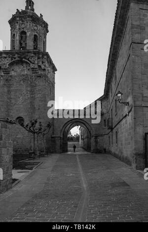 Am frühen Morgen ein pilger Spaziergänge durch die Iglesia del Crucifijo, Puente la Reina, Navarra, Spanien, entlang des Camino Frances. Stockfoto